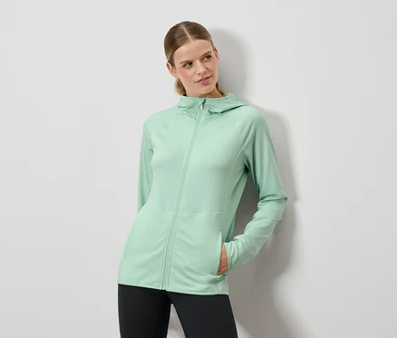 Femme posant dans un sweat à capuche vert menthe et un legging noir.