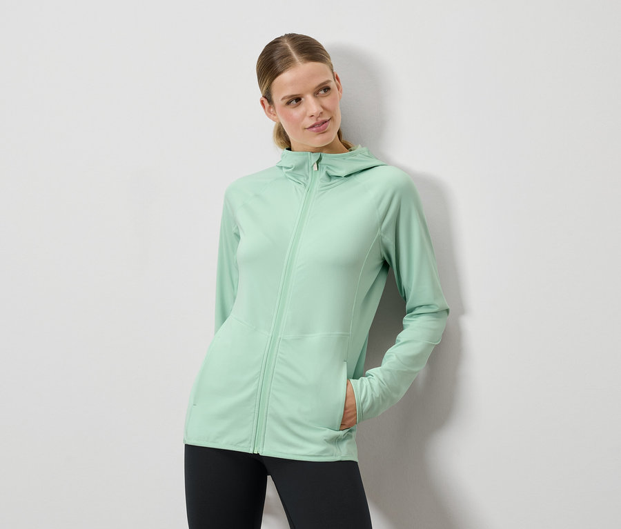 Femme posant dans un sweat à capuche vert menthe et un legging noir.