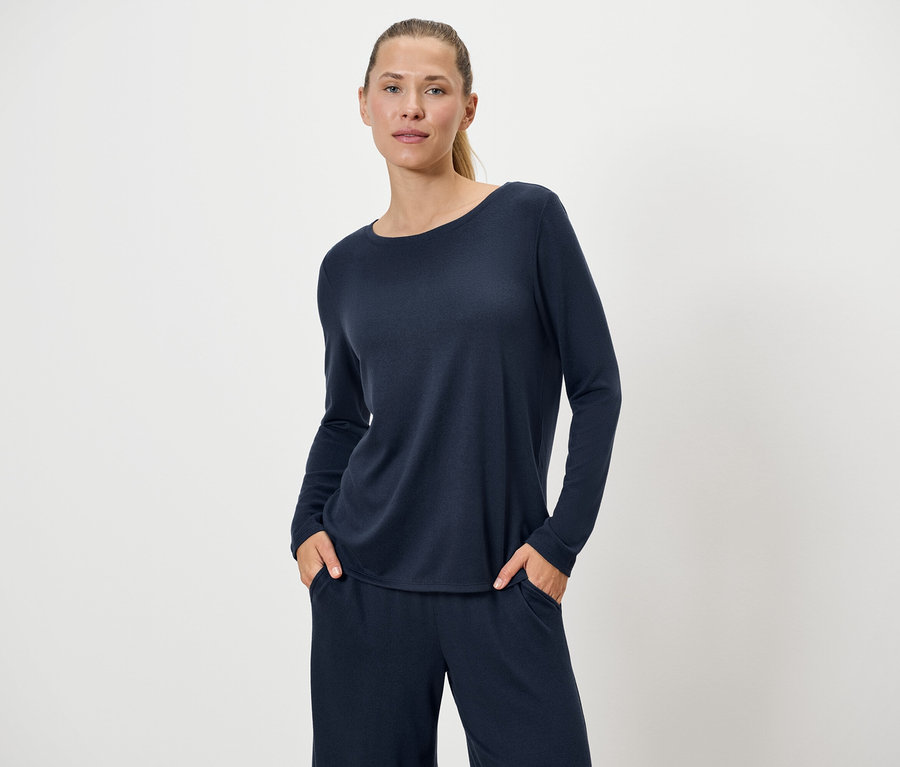 Femme en pull et pantalon bleu marine posant sur fond blanc.