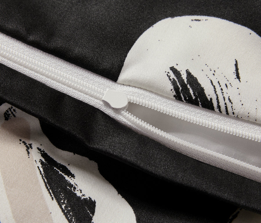 Gros plan sur une housse de couette noire et blanche avec une fermeture éclair partiellement ouverte.