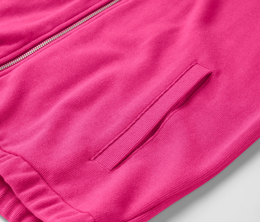 Détail d'une veste rose avec fermeture éclair et poche.