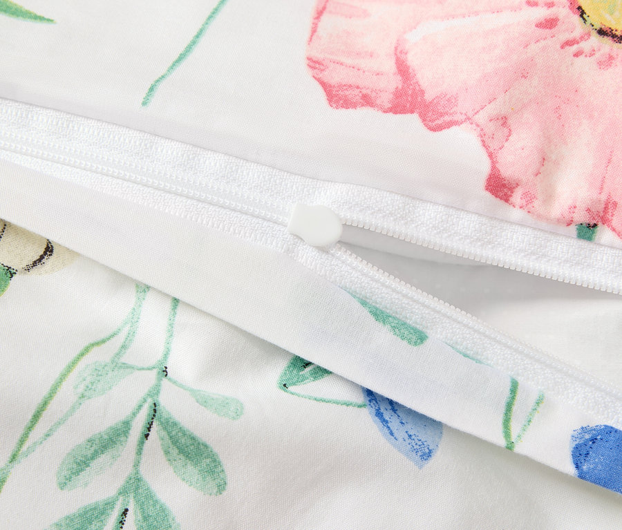 Détail d'une housse de couette blanche avec un motif floral et une fermeture éclair.
