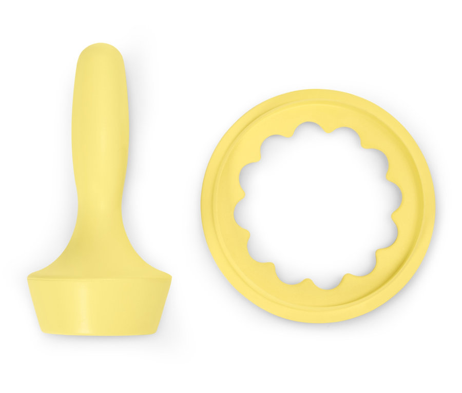 Un pilon à pâte jaune et un emporte-pièce sur un fond blanc.