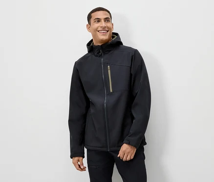 Un homme sourit et porte une veste noire à capuche.
