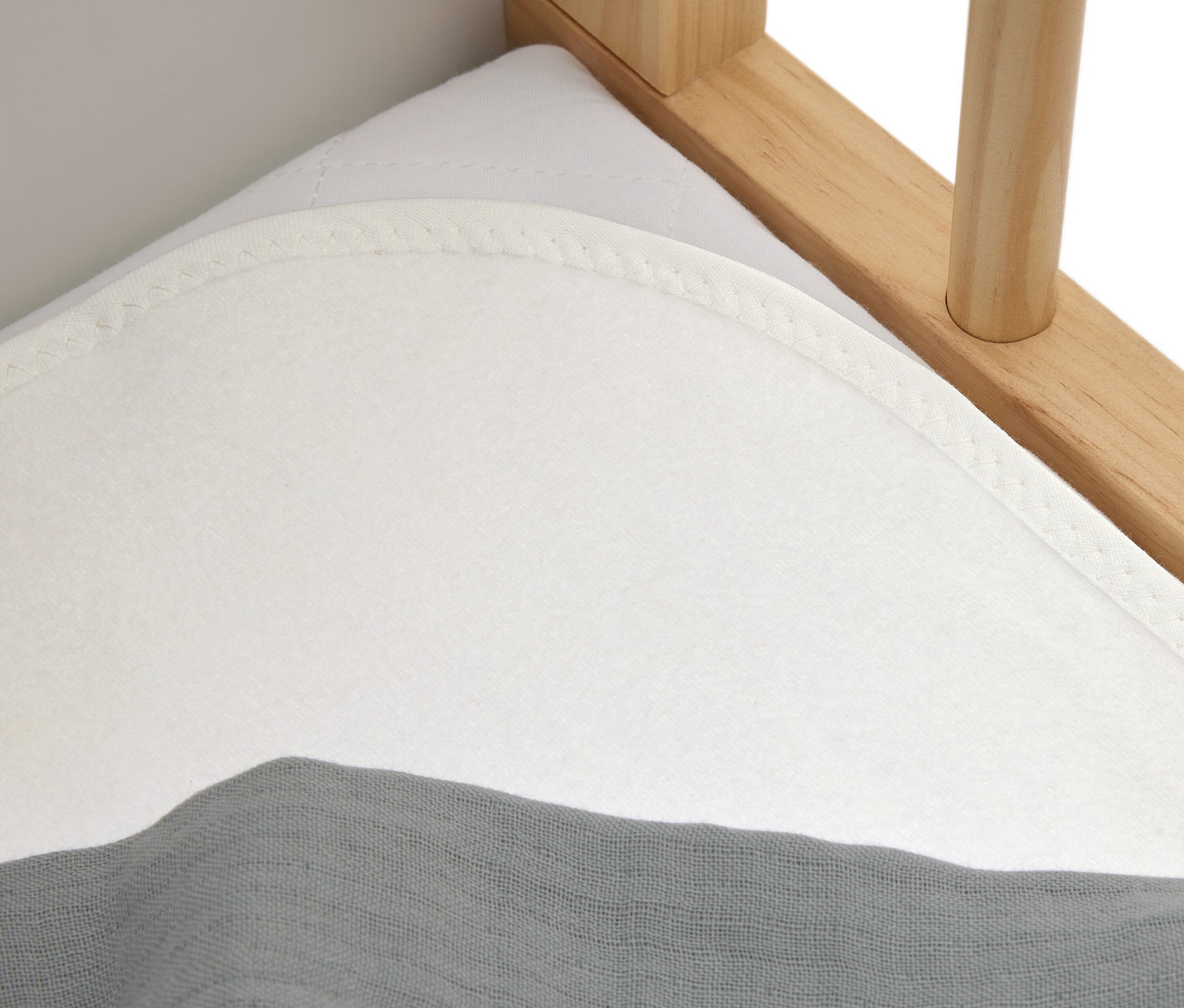 Gros plan d'un matelas blanc avec un tissu gris sur un lit en bois.