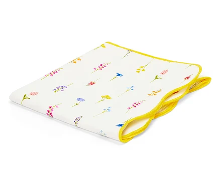 Un mouchoir en tissu blanc avec une bordure jaune et un motif floral est plié sur un fond blanc.