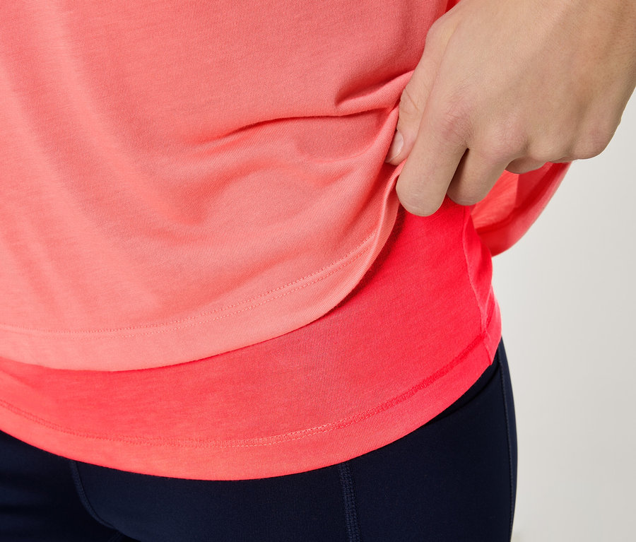 Gros plan d'une personne portant un haut de sport corail et un legging bleu marine.