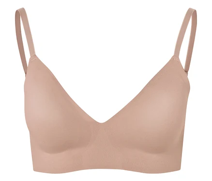 Gros plan d'un soutien-gorge couleur chair à fines bretelles sur fond blanc.