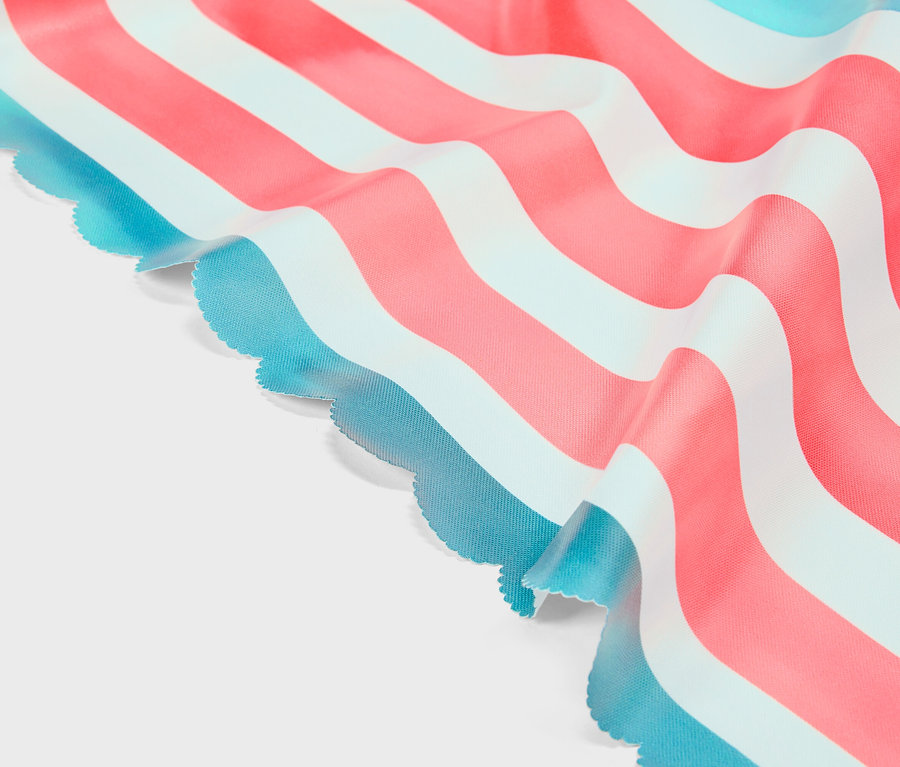 Gros plan d'un tissu à rayures roses, blanches et turquoises avec un bord ondulé.