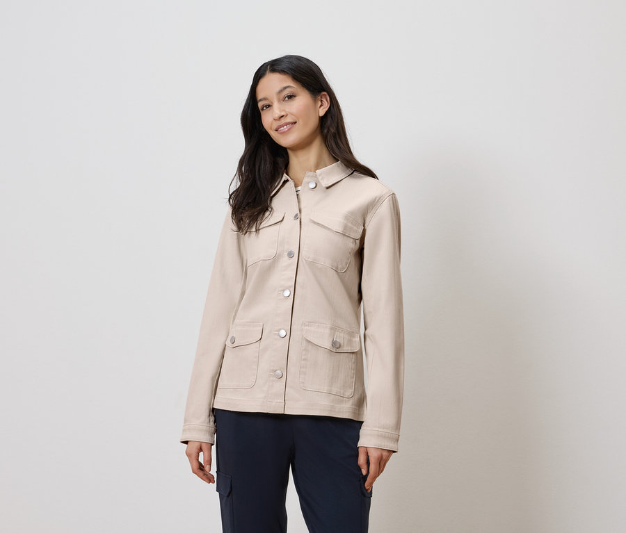 Femme portant une veste beige et un pantalon bleu.