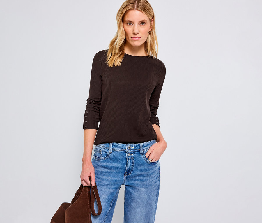 Femme portant un maillot côtelé Street One marron, un jean bleu et tenant un sac marron.