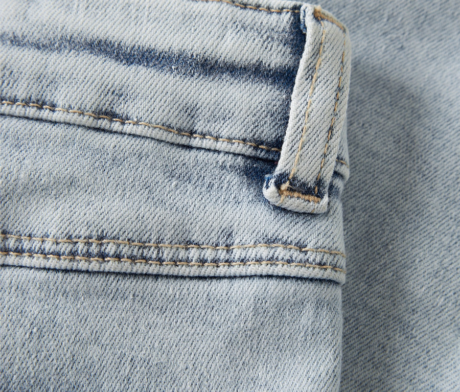 Gros plan d'un jean bleu clair avec une broderie cœur rose.