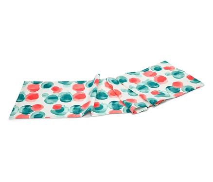 Un chemin de table avec un motif de points rouges et turquoises repose sur un fond blanc.