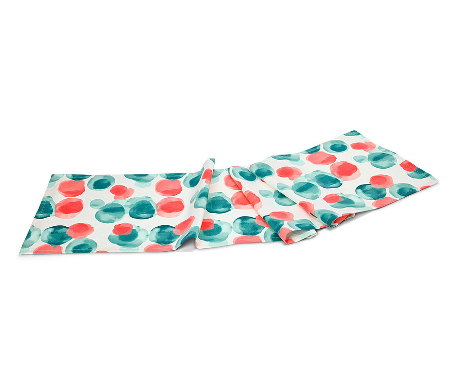 Un chemin de table avec un motif de points rouges et turquoises repose sur un fond blanc.