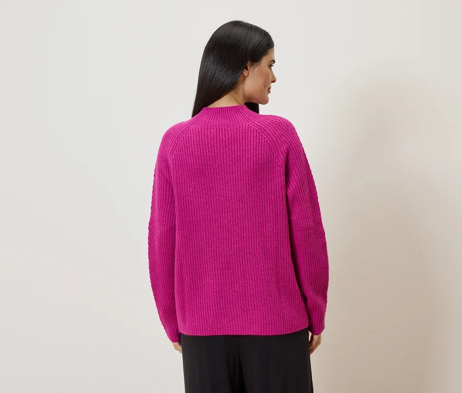 Vue arrière d'une femme aux longs cheveux foncés portant un pull en tricot rose et un pantalon noir.