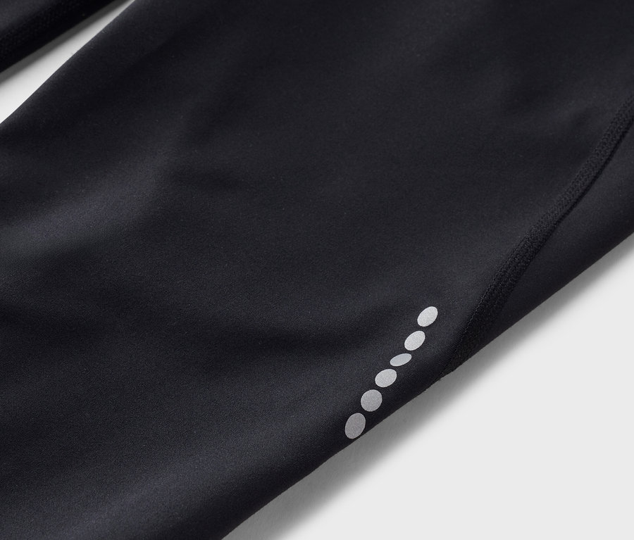 Gros plan sur un collant noir avec des points réfléchissants sur la jambe.
