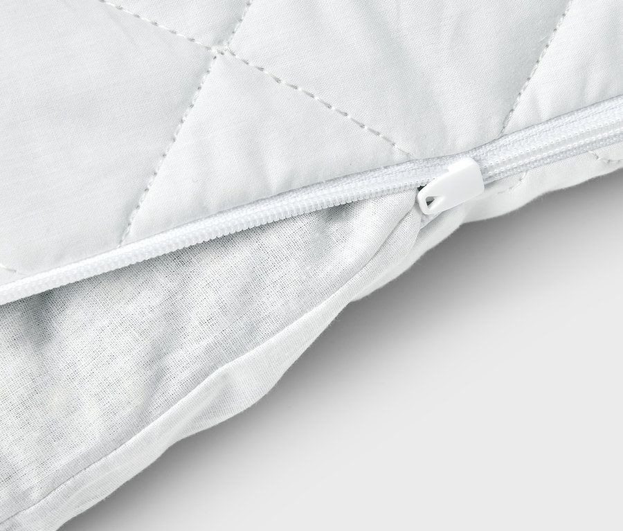 Vue détaillée d'un oreiller blanc avec fermeture éclair et housse matelassée.