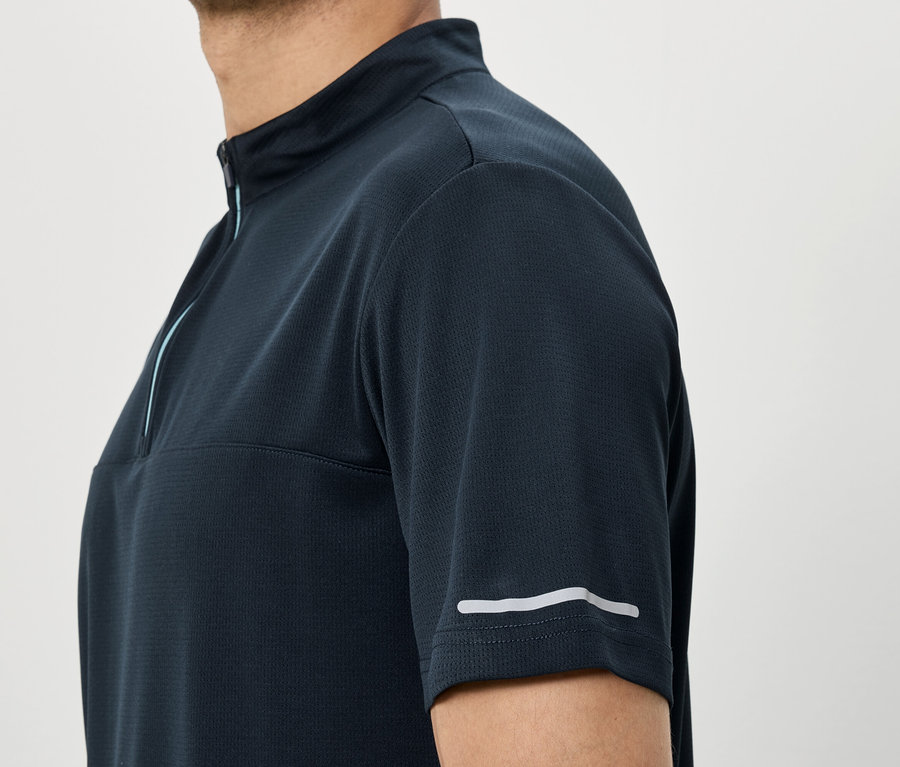 Homme portant une chemise bleu marine à manches courtes avec fermeture éclair et bande réfléchissante sur la manche.