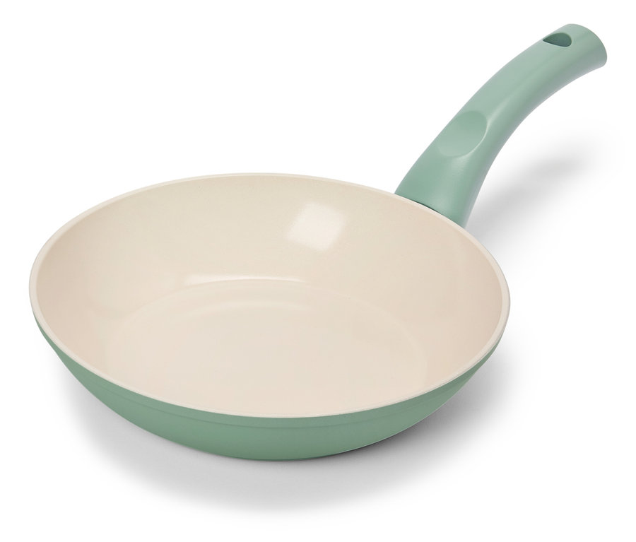Une poêle à frire vert clair avec un intérieur crème repose sur un fond blanc.