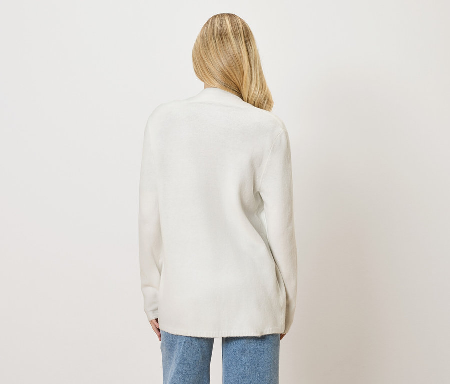 Vue arrière d'une femme blonde portant un cardigan blanc et un jean.
