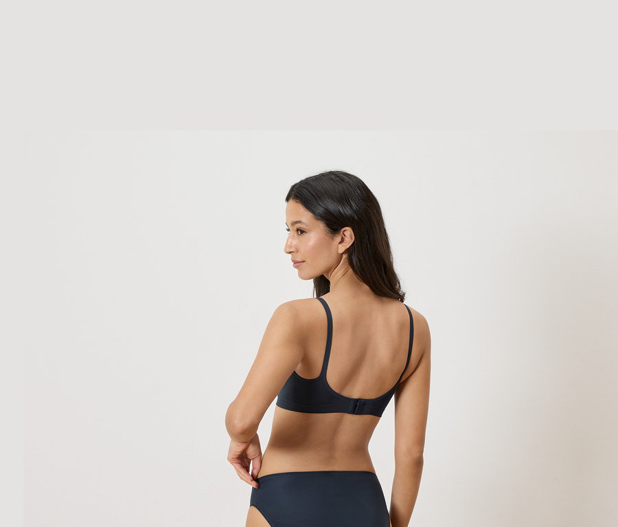 Femme portant un soutien-gorge et une culotte bleu marine, vue de dos.