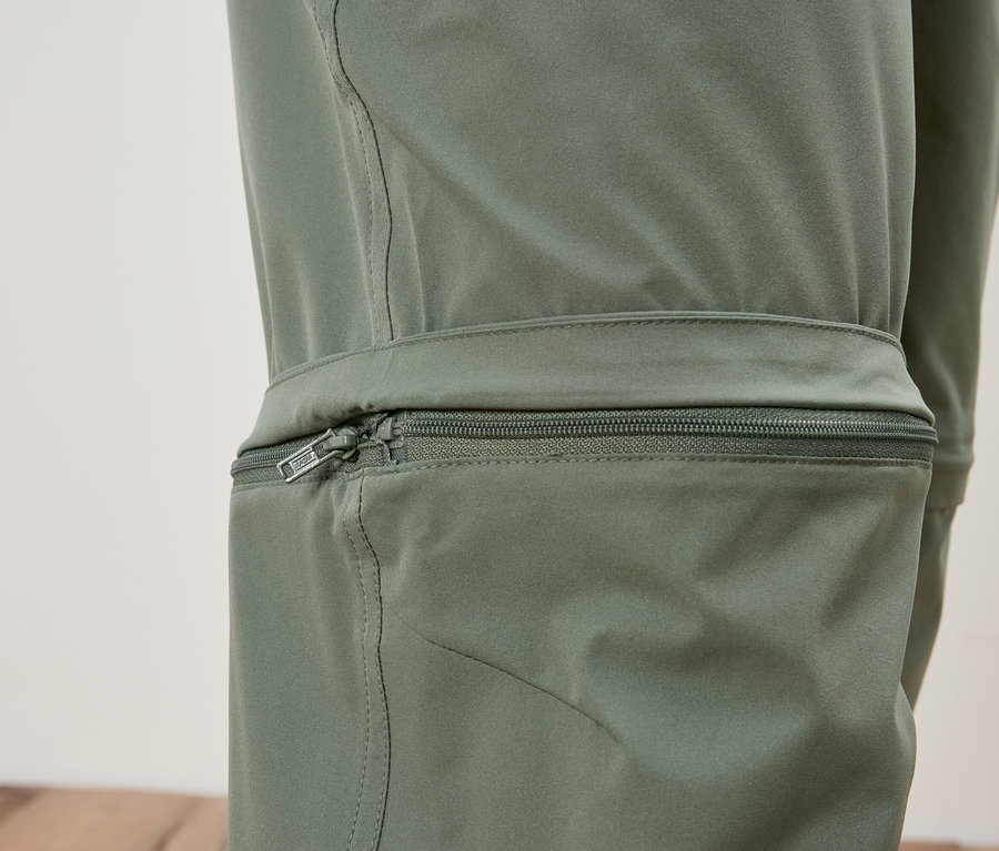 Gros plan sur la jambe d'un pantalon vert olive avec fermeture éclair.