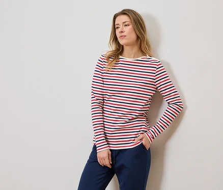 Femme portant un t-shirt rayé à manches longues et un pantalon de jogging bleu, une main dans la poche.