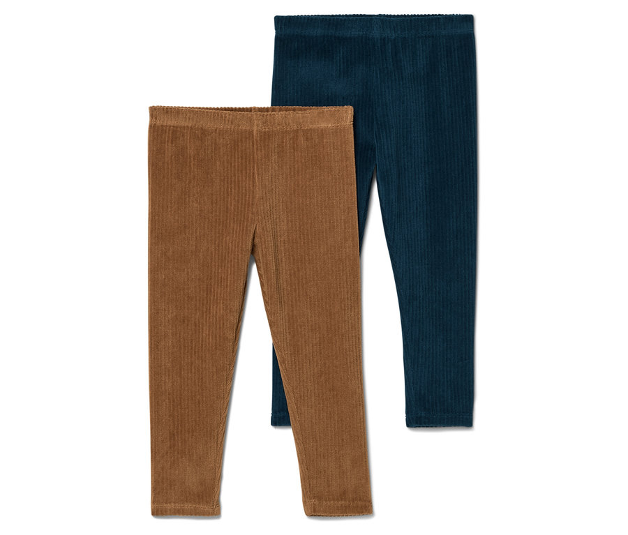 Un pantalon en velours côtelé marron et un pantalon bleu marine sont posés l'un sur l'autre sur un fond blanc.