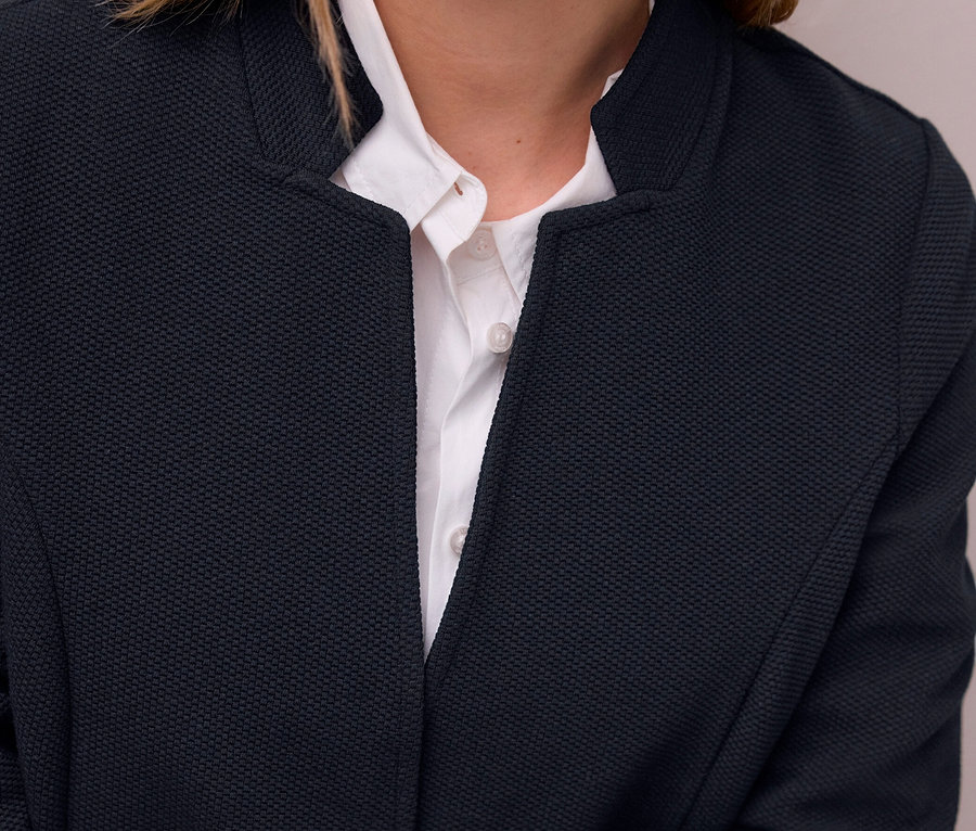 Gros plan d'une personne portant un blazer en jersey Street One bleu foncé texturé sur une chemise blanche.