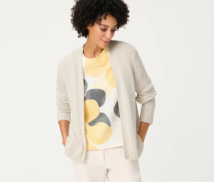 Femme portant un cardigan en lin Olsen sur un t-shirt à cercles jaunes et gris, les mains dans les poches.