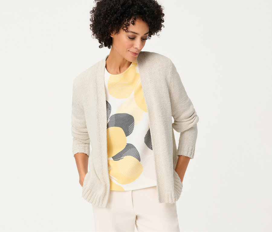 Femme portant un cardigan en lin Olsen sur un t-shirt à cercles jaunes et gris, les mains dans les poches.