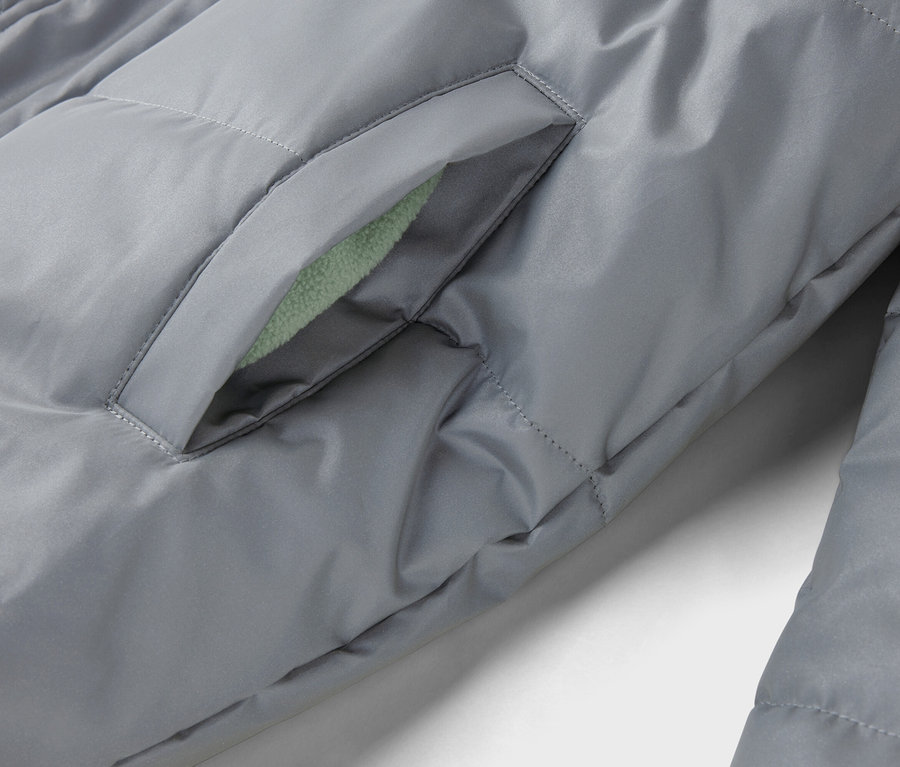 Gros plan sur une veste matelassée grise avec une poche dont la doublure est vert clair.