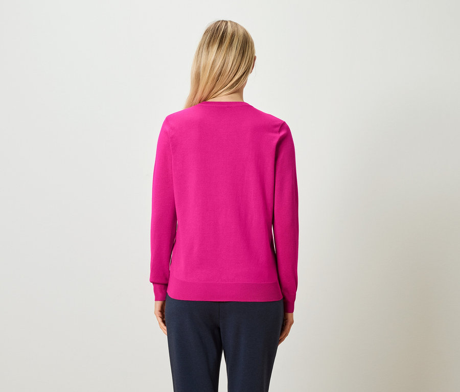 Vue de dos d'une femme aux cheveux blonds relevés, portant un pull rose et un pantalon bleu marine.