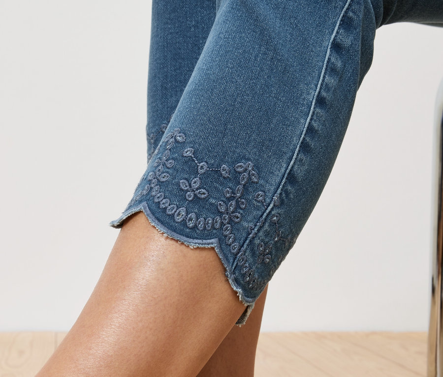Gros plan sur un jean avec broderie ajourée en bas de jambe.