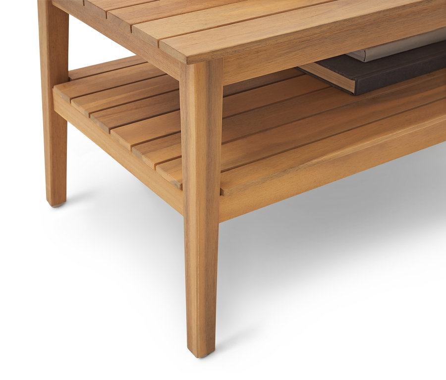 Gros plan d'une table d'appoint en bois marron clair avec une étagère et un livre dessus.