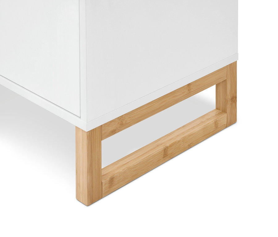 Coin inférieur d'un meuble blanc reposant sur un cadre en bois clair.