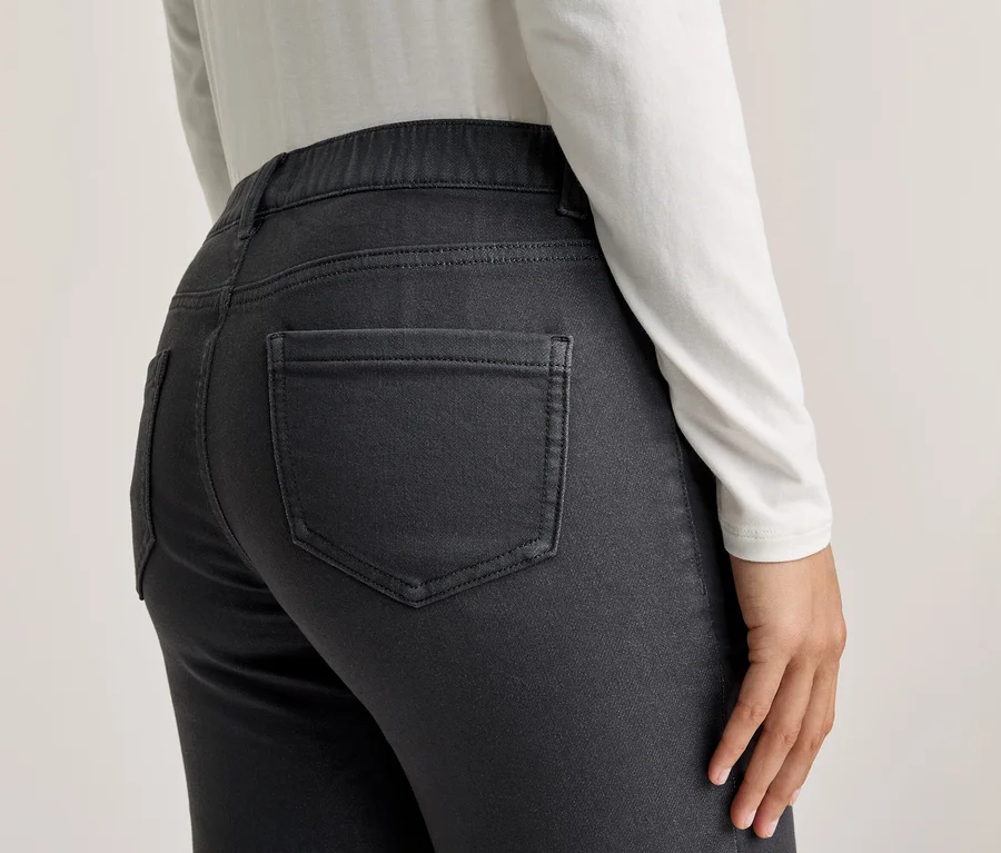 Vue de dos d'une personne portant un haut blanc à manches longues et un pantalon gris foncé avec des poches arrière.