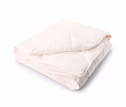 Une couette matelassée de couleur crème, soigneusement pliée en deux, sur un fond blanc.