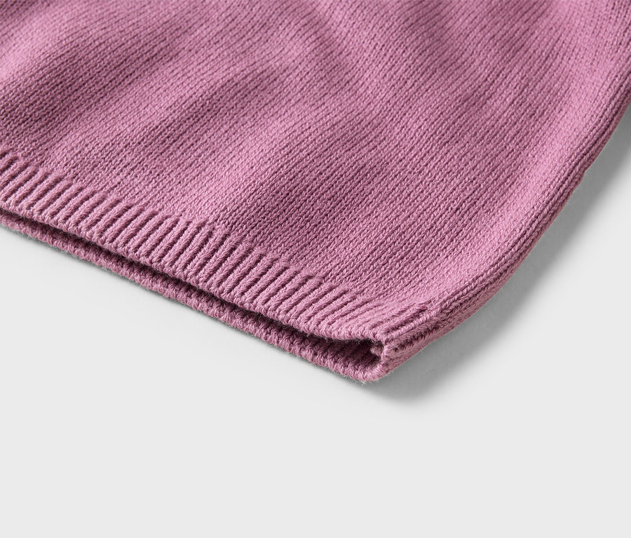 Gros plan d'un tissu tricoté rose avec un ourlet côtelé, montrant la texture des mailles.