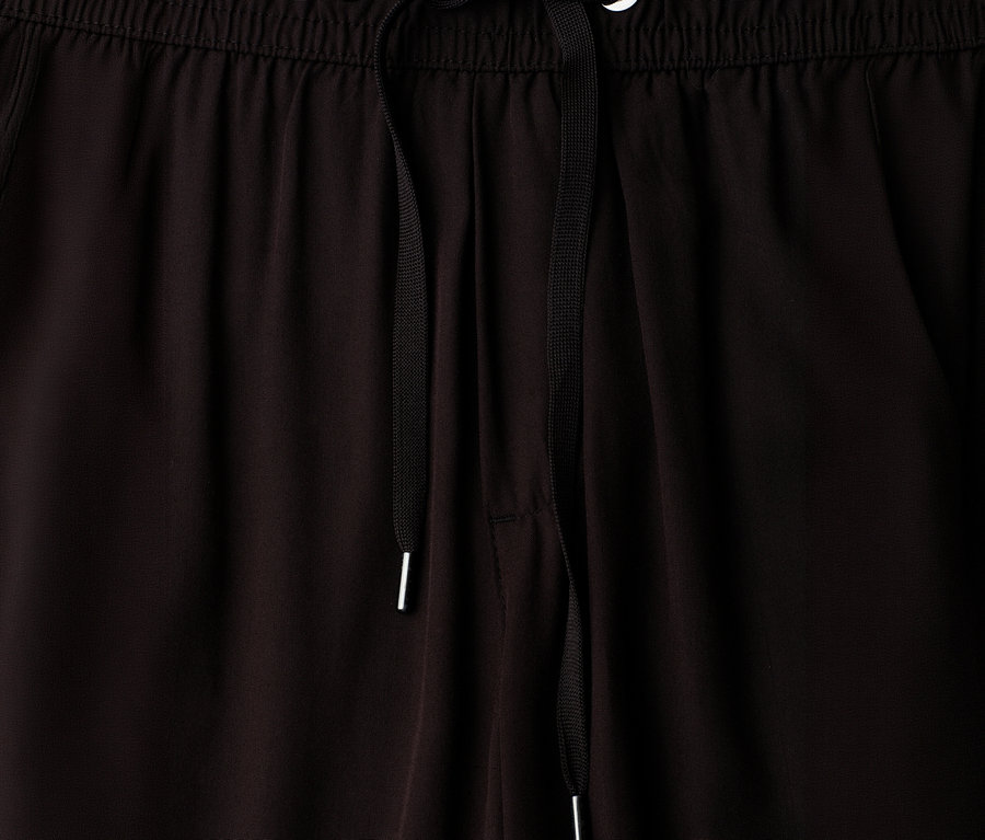 Gros plan sur la taille élastique d'un pantalon culotte 7/8 noir Street One EMMA, avec un cordon de serrage noir à embouts argentés passant par deux œillets argentés.