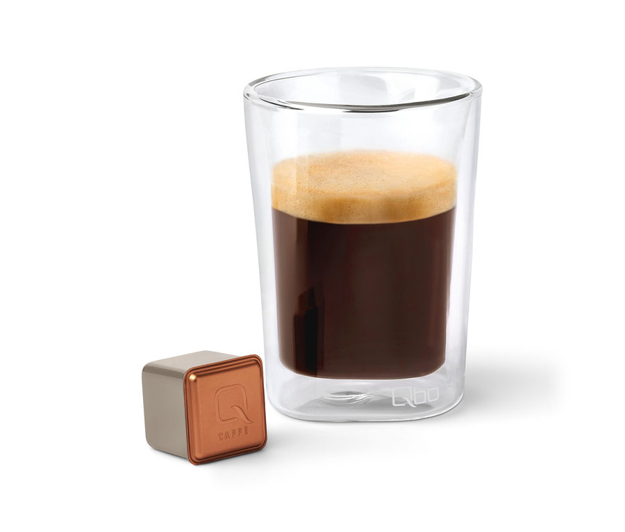 Une capsule de café Qbo Caffè BUNA ENTETA à côté d'un verre de café.