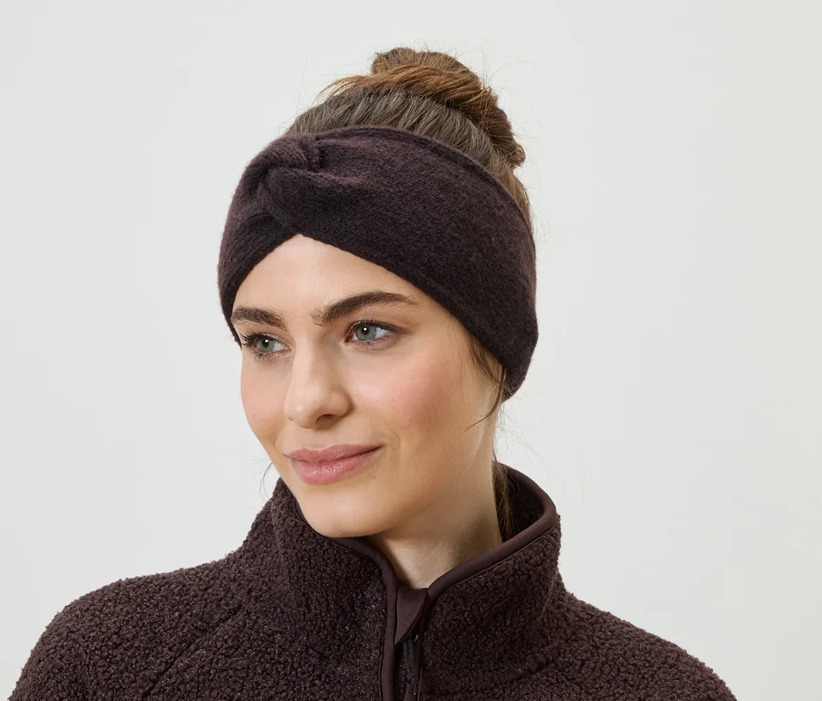 Portrait d'une femme portant un bandeau marron et un pull en polaire, regardant vers la gauche.