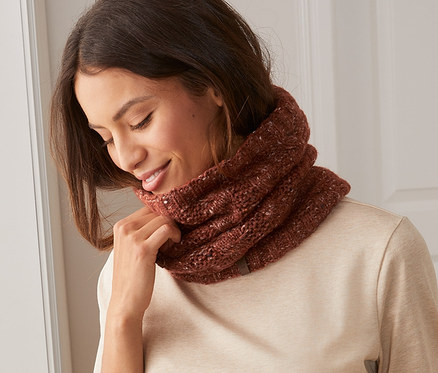 Femme ajustant une écharpe tube en maille autour de son cou.