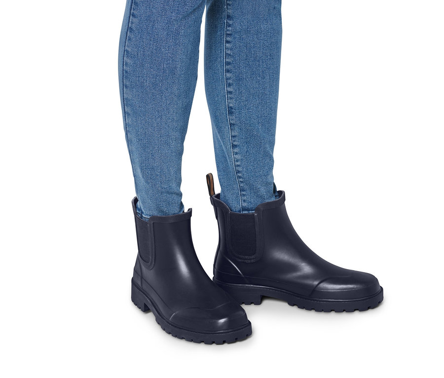 Jambes en jean et bottines de pluie.