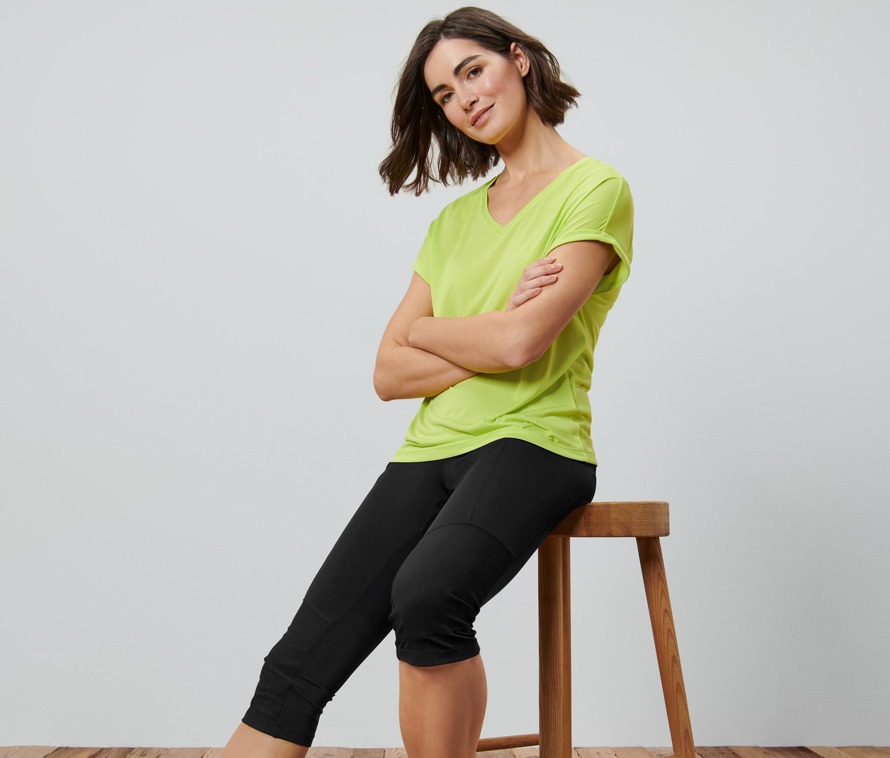 Femme assise sur un tabouret, les bras croisés, portant un corsaire de trekking 3/4 noir.