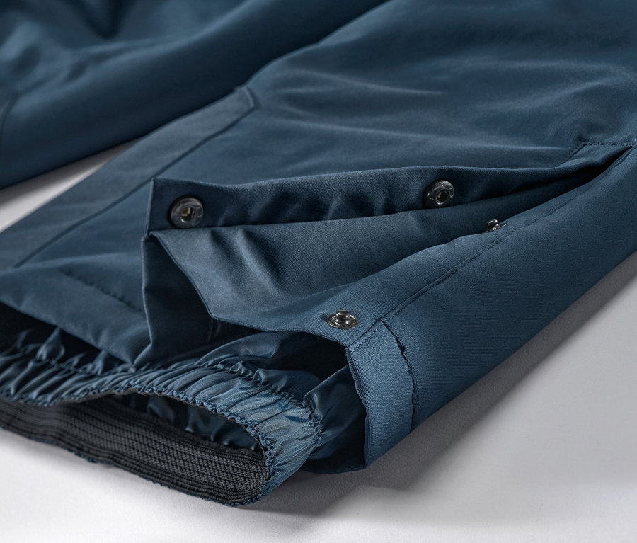 Gros plan sur un pantalon de ski et de snowboard bleu marine avec des boutons.