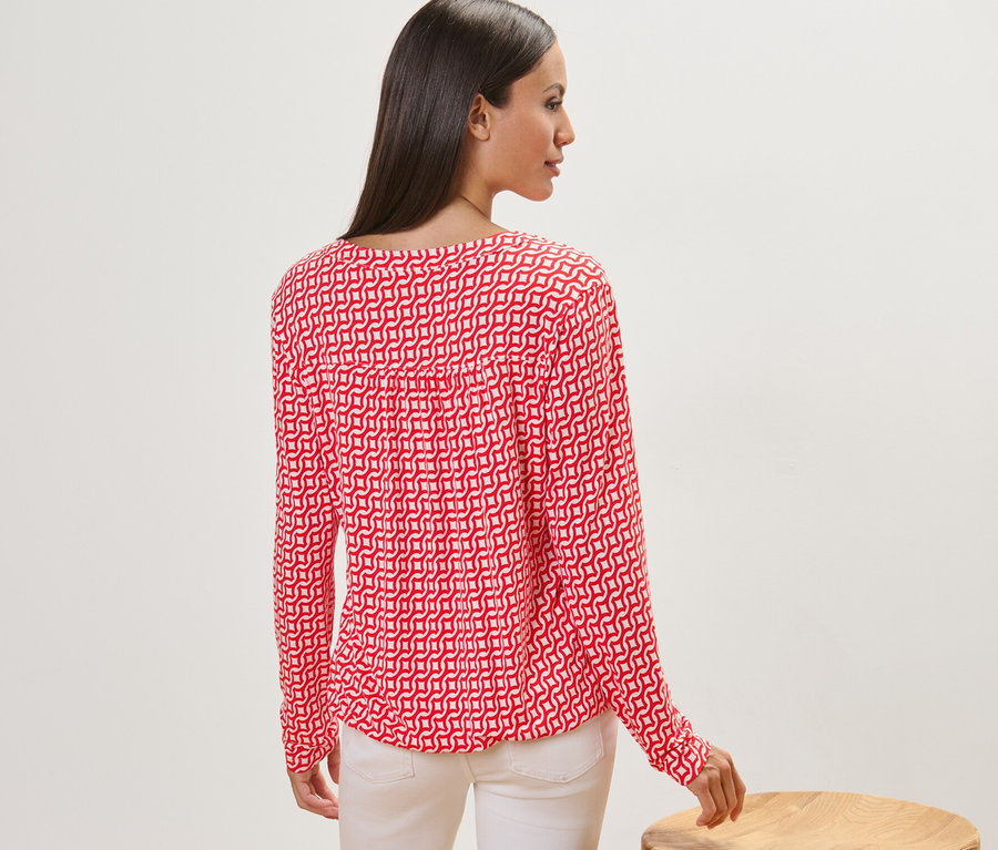Une femme, vue de dos, porte une blouse imprimée rouge.