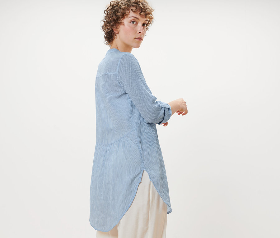 Femme posant en chemisier long à rayures.