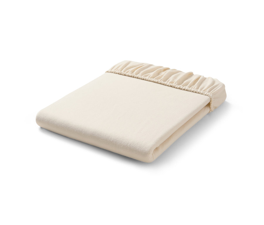 Un drap-housse en molleton crème plié sur un fond blanc.
