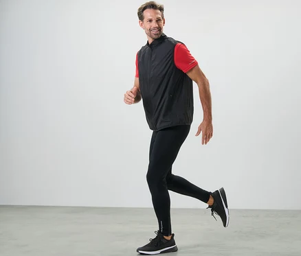 Homme courant en legging de sport noir et gilet.